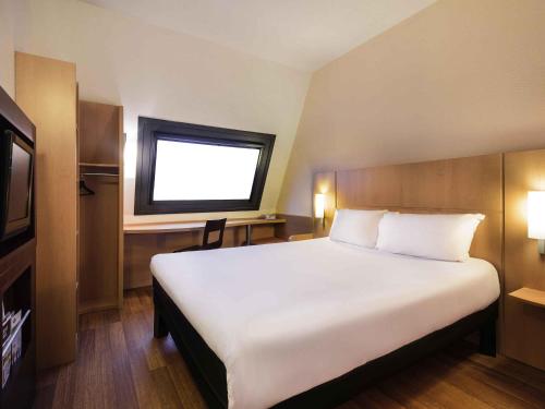 a bedroom with a large white bed with a window at Ibis Bilbao Centro in Bilbao