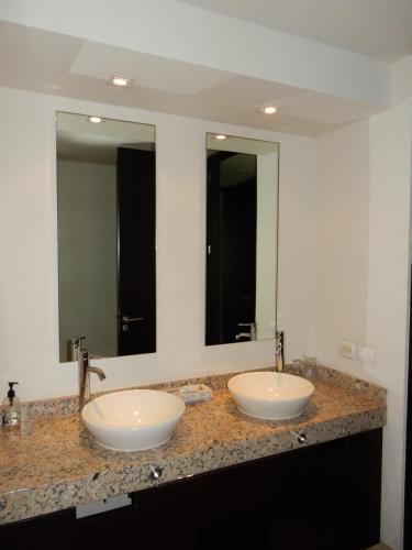 two sinks in a bathroom with two mirrors at La Isla Gran Cayman 904 in Acapulco