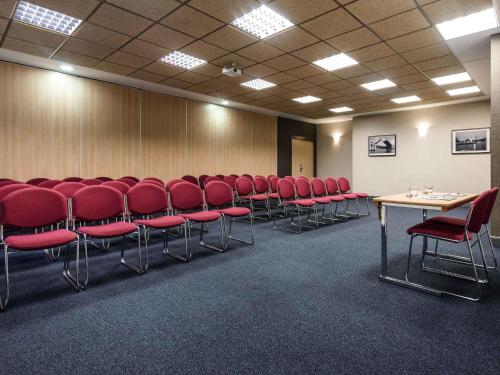 a conference room with red chairs and tables in it at Ibis Bilbao Centro in Bilbao