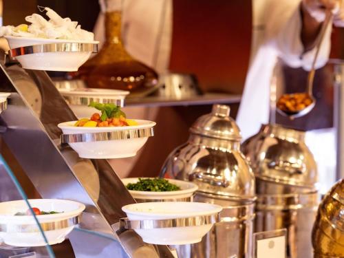 a buffet with plates of food on a shelf at Pullman ZamZam Makkah in Makkah