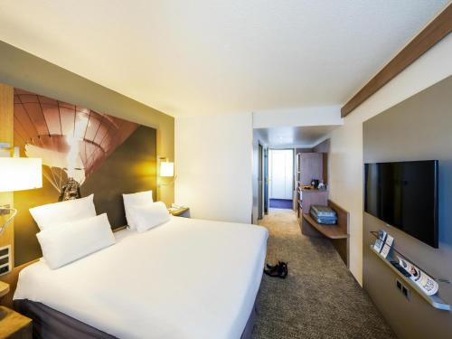a hotel room with a bed and a flat screen tv at Mercure Vienne Sud Chanas in Chanas