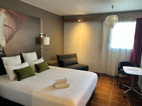 a hotel room with a large bed and a chair at Mercure Vienne Sud Chanas in Chanas