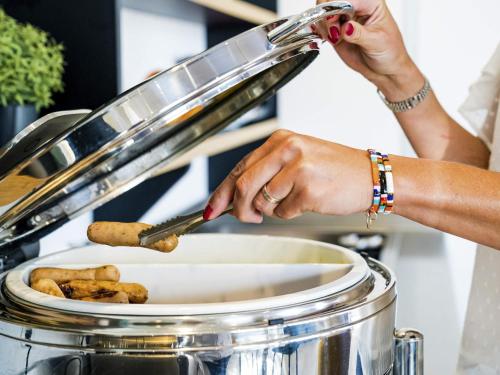 a woman stirring a pot with a knife at Mercure Vienne Sud Chanas in Chanas
