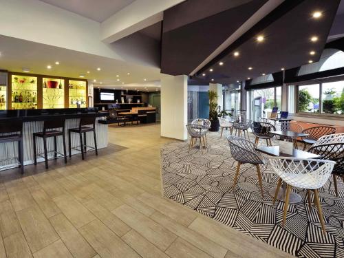 a lobby with a bar and tables and chairs at Mercure Vienne Sud Chanas in Chanas