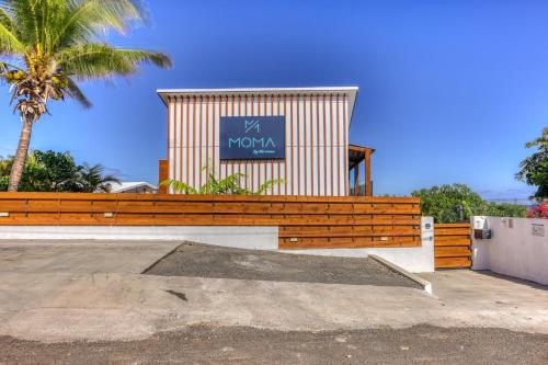 a building with a sign on top of a wooden fence at Le Moma by the ocean in Trois Bassins
