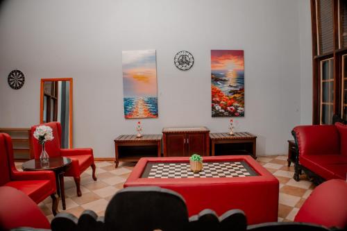 a living room with red chairs and a table and a clock at Hotel & Apartment Serene in Dar es Salaam