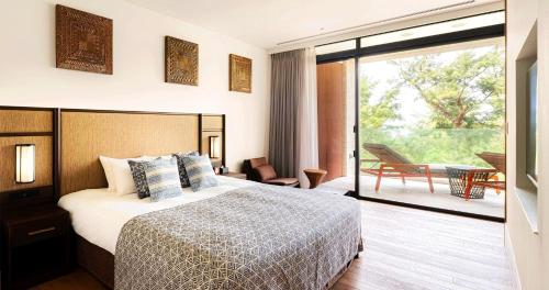 a hotel room with a bed and a balcony at UMITO Okinawa Onnason in Onna