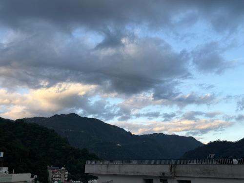a cloudy sky with mountains in the background at The Little House in Rishīkesh