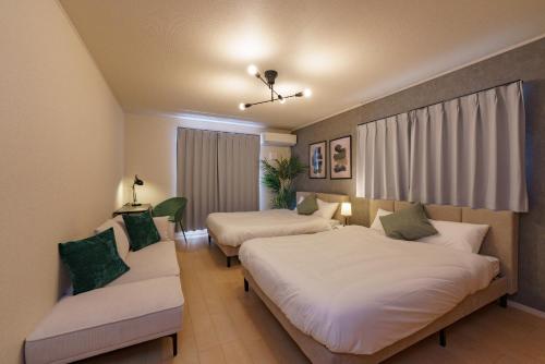 ein Hotelzimmer mit zwei Betten und einer Couch in der Unterkunft Nagoya15min 6 beds Free Parking 3BR 13guests 100sqm in Nagoya