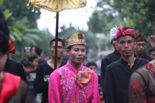 a group of men walking down a street with an umbrella at Tetebatu Indah Homestay in Tetebatu