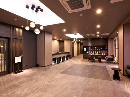a large lobby with tables and chairs in a building at Hotel Route Inn Grand Moriya Ekimae in Moriya