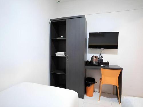 a bedroom with a desk with a tv and a chair at Hotel Ahava in Magelang