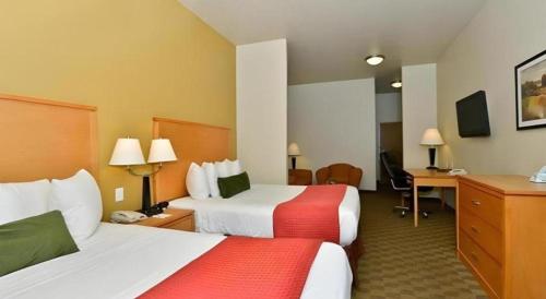 a hotel room with two beds and a desk at Best Western Plus Guymon Hotel and Suites in Guymon