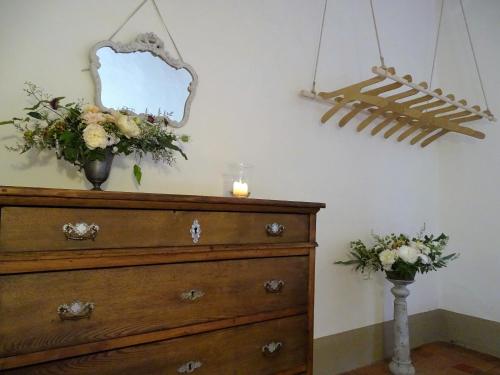 a dresser with a mirror and flowers on top of it at Podere Pievina Delle Corti - Dimora di Campagna in Sinalunga