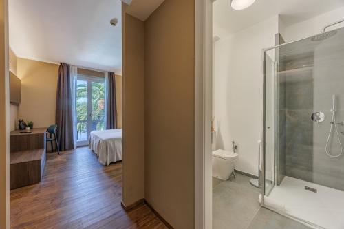 a bathroom with a shower and a toilet and a bedroom at Hotel San Marco in Bardolino