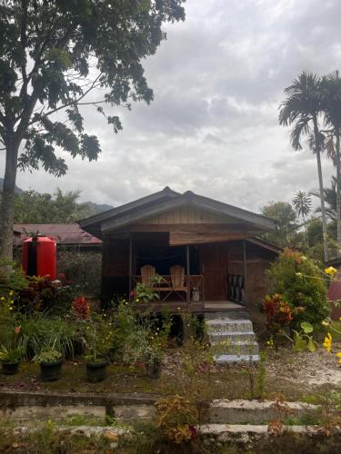 a house with a table and chairs in a garden at Cinta alam inn in Kutacane