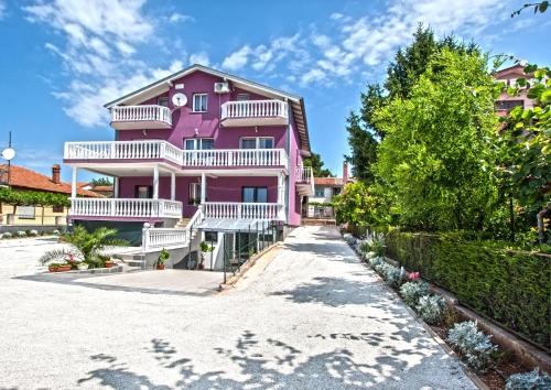 a pink house with white balconies on a beach at Apartments Villa Excellente Belvedere in Pula
