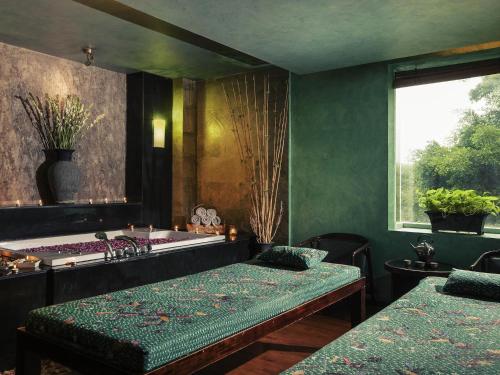 a green room with two beds and a bath tub at Mercure Surabaya Grand Mirama in Surabaya
