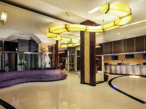 a lobby with purple furniture and a large chandelier at Mercure Surabaya Grand Mirama in Surabaya