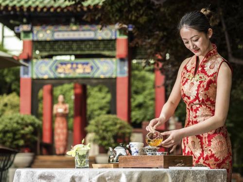 a woman in a red dress preparing food at Sofitel Legend People's Grand Hotel Xi'an in Xi'an