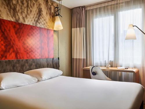 a hotel room with a white bed and a window at ibis Bordeaux Centre Bastide in Bordeaux