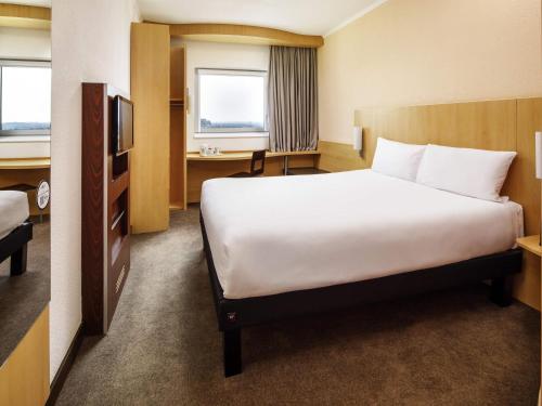 a hotel room with a large bed and a desk at ibis Nottingham Centre in Nottingham