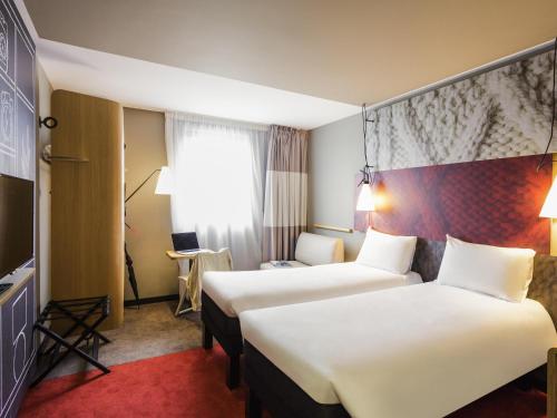 a hotel room with two beds and a desk at ibis Bordeaux Centre Bastide in Bordeaux