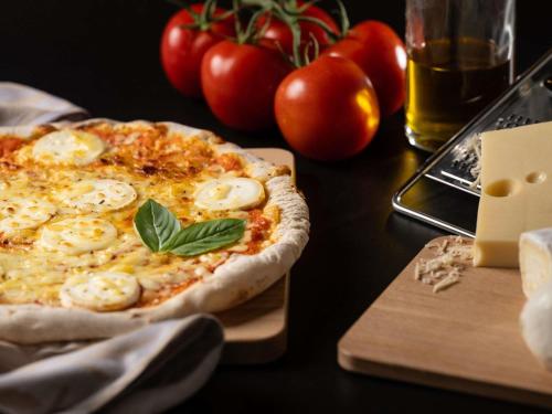 a pizza sitting on top of a table with tomatoes at ibis Bordeaux Centre Bastide in Bordeaux