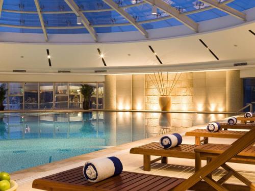 a swimming pool with benches in a building at Sofitel Nanjing Galaxy in Nanjing