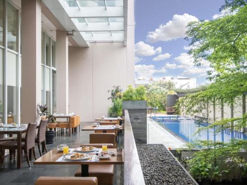 un ristorante all'aperto con piscina, tavoli e sedie di Novotel Bandung a Bandung