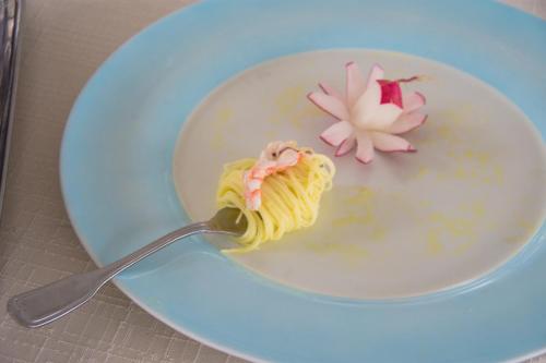 a bowl of soup with a fork with pasta and a flower at Grand Hotel Moon Valley in Vico Equense