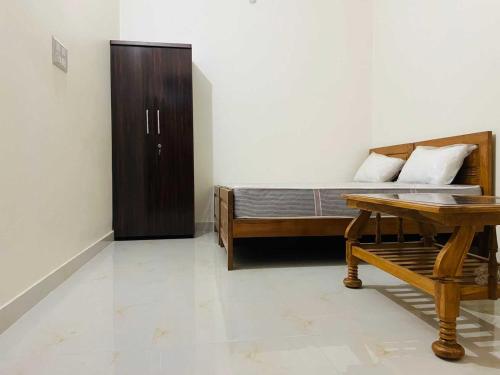 a bedroom with a bed and a wooden table at Hotel O Ananta Grand in Malhour