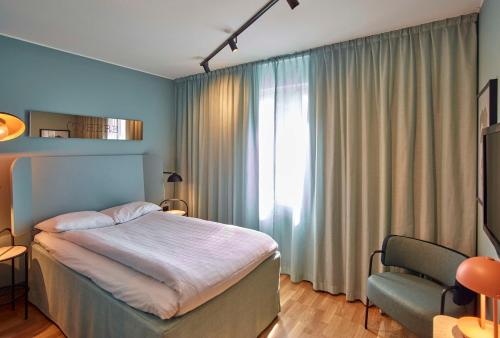 a bedroom with a bed and a chair and a window at Scandic Borlänge in Borlänge