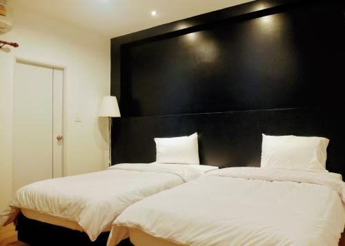 two beds in a room with a large black headboard at The Resto in Udon Thani
