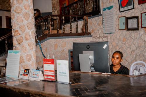 a man sitting at a desk with a computer at Hotel & Apartment Serene in Dar es Salaam