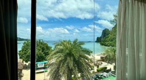 a view of a beach from a window with a palm tree at Phi Phi Nice Beach Hotel Hip in Phi Phi Don