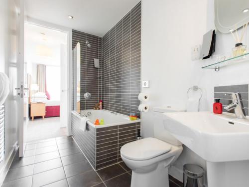 a bathroom with a toilet and a sink and a tub at PREMIER SUITES Liverpool in Liverpool