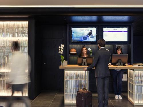a man standing at a counter in front of two women at Mercure Paris Boulogne in Boulogne-Billancourt