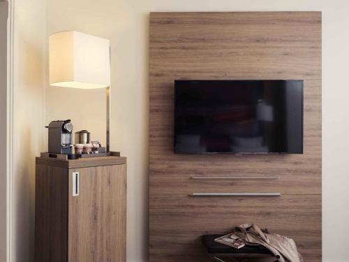 a living room with a flat screen tv on a wall at Mercure Paris Boulogne in Boulogne-Billancourt