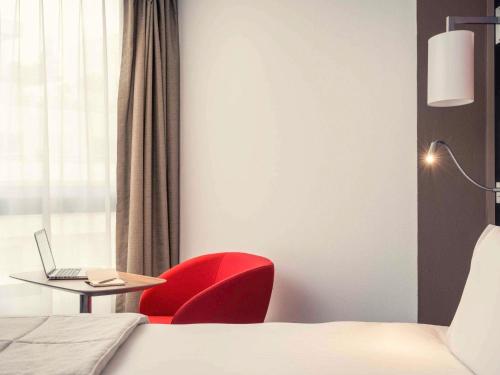 a room with a red chair and a table with a laptop at Mercure Paris Boulogne in Boulogne-Billancourt