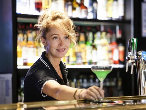 a woman sitting at a bar with a drink at Mercure Paris Boulogne in Boulogne-Billancourt