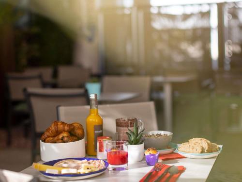 ein Tisch mit einem Teller Essen und einer Flasche Wein in der Unterkunft Novotel Suites Marseille Centre Euromed in Marseille