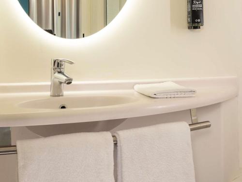 a bathroom with a sink and a mirror and towels at ibis Marseille Centre Euromed in Marseille