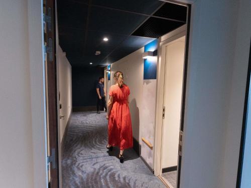 a woman in a red dress walking down a hallway at ibis Marseille Centre Euromed in Marseille