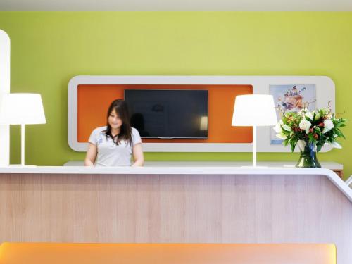a woman sitting at a counter in a waiting room at ibis budget Antwerpen Centraal Station in Antwerp