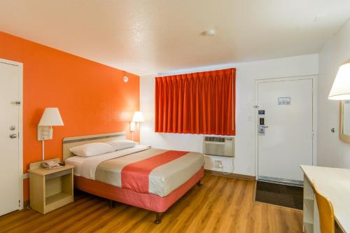 a hotel room with a bed with an orange wall at Motel 6-Schiller Park, IL - Chicago O'Hare in Rosemont