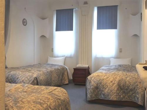 a hotel room with two beds and two windows at Arabian Art Hotel & Gallery in Onjuku