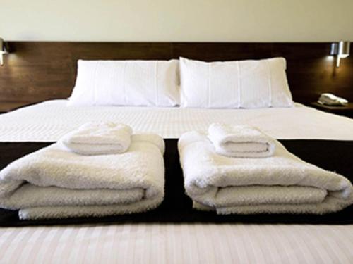 a bedroom with a bed with towels on it at Mercure Bunbury Sanctuary Golf Resort in Bunbury