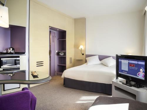 a hotel room with a bed and a television at Novotel Marrakech Hivernage in Marrakech