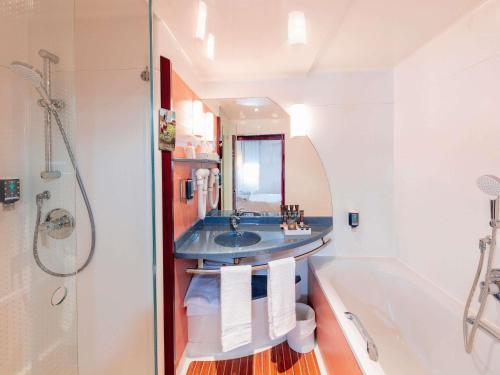 a bathroom with a tub and a sink and a bath tub at Novotel Marrakech Hivernage in Marrakech